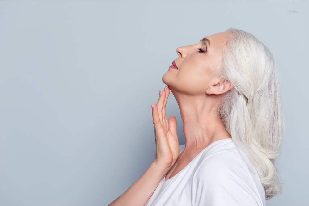 Woman caressing her neck. Neck lift concept.